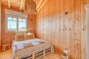 a bedroom with a bed in a wooden wall at Maison de la plage in Hourtin