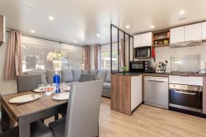 Una cocina y una sala de estar con una mesa de madera y una cocina y un comedor. en Mobilhome Soleia 2023 Mar Estan 4x, en Canet-en-Roussillon