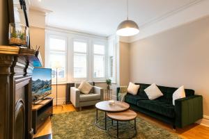 ein Wohnzimmer mit einer grünen Couch und einem Tisch in der Unterkunft The Shakespeare -5Bed 3Bath in Ealing