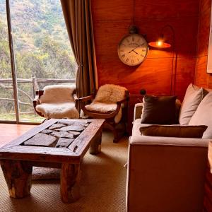 a living room with a table and a clock on the wall at Casa Nilhue junto al río in Lo Barnechea
