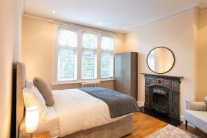Schlafzimmer mit einem Bett, einem Spiegel und einem Kamin in der Unterkunft The Shakespeare -5Bed 3Bath in Ealing