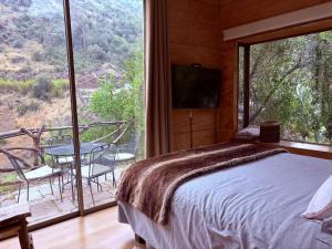 a bedroom with a bed and a balcony with a table at Casa Nilhue junto al río in Lo Barnechea