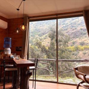 a dining room with a table and a large window at Casa Nilhue junto al río in Lo Barnechea