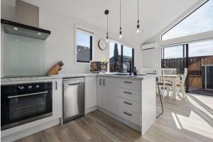 a kitchen with white cabinets and a large window at Amie's Charming Villa in Tauranga
