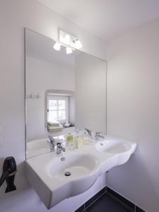 a white bathroom with a sink and a mirror at La Moutière in Colonzelle