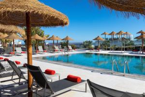a swimming pool with chairs and umbrellas at Sol Fuerteventura Jandia - All Suites in Morro del Jable