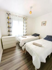 3 camas en una habitación con paredes blancas y suelo de madera en Le clos de Valletot, en Valletot