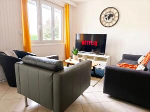 a living room with two couches and a tv at Le Clos de Valletot in Valletot