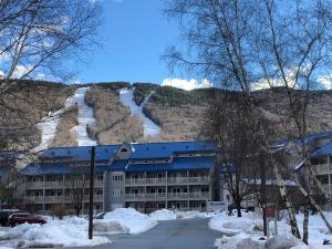 a building with a snow covered mountain in the background at Loon Mountain Retreat with Pool and Hot Tub in Lincoln