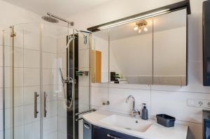 a bathroom with a sink and a shower with a mirror at Haus mit Garten und Kamin in Wilhelmshaven +24 photos