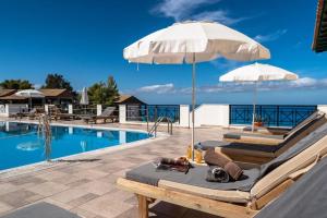 una piscina con due lettini e un ombrellone di Sunset Premium Studio 13 a Ayios Nikitas