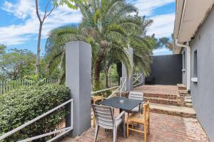 a patio with a table and chairs and palm trees at The Cozy 2 bedroom Apartment in Roodepoort