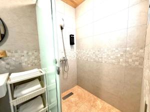 a shower with a glass door in a bathroom at 看海季節&聽海約定精緻旅店 in Magong