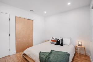 a white bedroom with a bed with a green blanket at Hillside House with DTLA Views in Los Angeles +34 photos