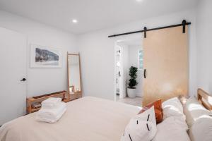 a bedroom with a bed with white sheets and pillows at Hillside House with DTLA Views in Los Angeles