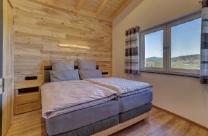 a bedroom with a wooden wall and a bed with a window at Landhaus Rachelblick in Eppenschlag