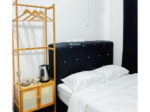 a bed with a black headboard next to a table with a coffee maker at My Room Sri Aman in Kampong Lamanak