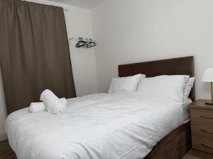 a bedroom with a large bed with white sheets and pillows at Spacious 3 Bedroom With Garden and Free Parking in Rawmarsh