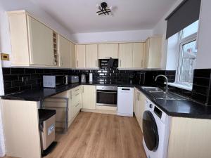 a kitchen with white appliances and black counter tops at Spacious 3 Bedroom With Garden and Free Parking in Rawmarsh