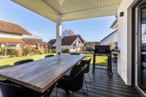 an outdoor patio with a wooden table and chairs at Ferienhaus Lencer in Ühlingen-Birkendorf