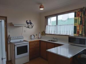 eine Küche mit einer Spüle, einem Herd und einem Fenster in der Unterkunft Beachside Townhouse Dunedin in Dunedin