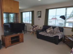 ein Wohnzimmer mit Couch und Flachbildfernseher in der Unterkunft Beachside Townhouse Dunedin in Dunedin