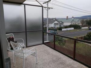 ein Balkon mit zwei Stühlen und Blick auf eine Straße in der Unterkunft Beachside Townhouse Dunedin in Dunedin