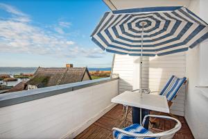 una mesa y sillas en un balcón con sombrilla en Aquarius Ferienwohnung Usedom, en Loddin