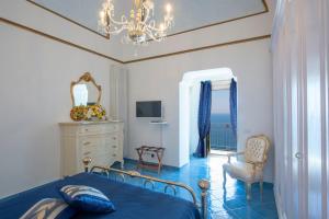 a bedroom with a blue bed and a chandelier at Luxury Villa Soleluna con jacuzzi in Praiano