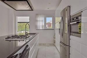 a white kitchen with a stove and a refrigerator at The Beautiful White Villa in Kortenberg +37 photos