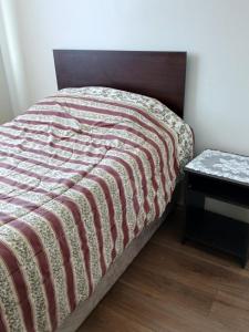 een bed in een kamer met een tafel en een sprei bij Aires in La Serena