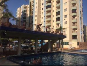 a swimming pool with people sitting on a balcony next to a building at Apartamento 3 quarto com ótima área de lazer in Caldas Novas +7 photos
