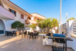 a patio with tables and chairs and a grill at Luxury 12 in Tuglie