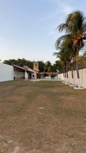 a yard with palm trees in front of a building at Casa para temporada pertinho do mar in São-José-do-Ribamar