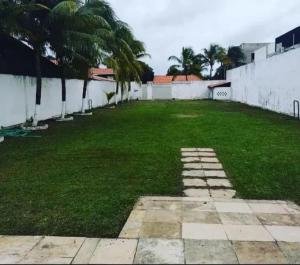 a large yard with palm trees and a white wall at Casa para temporada pertinho do mar in São José de Ribamar +11 photos