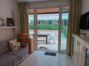 a living room with a couch and a sliding glass door at Rex Lo Scoglietto Punta Ala in Punta Ala