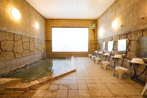 a swimming pool in a room with chairs and a large window at ホテルララプラス in Nirasaki
