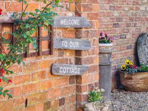 a brick wall with signs that say welcome to our cottage at The Pottery in Horncastle