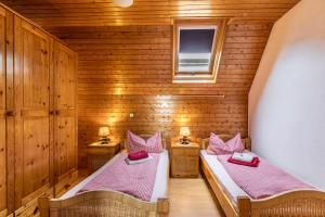 two beds in a room with wooden walls at Apartmenthaus Ferienwohnungen Sila in Weinstadt