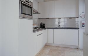 a white kitchen with white cabinets and a microwave at Lobster in Egmond aan Zee