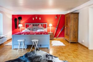 a bedroom with a red wall and a bed with stools at Ferienwohnung Hedwig in Breitnau