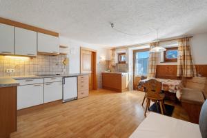 a kitchen with white cabinets and a table in it at Wegscheiderhof in Dobbiaco