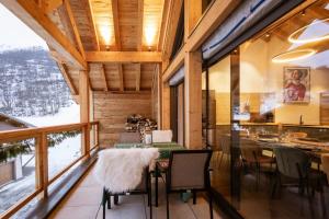 a dining room with a table and chairs and a large window at Chalet-Spa Le Cervin in Valloire