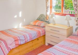 a bedroom with two beds and a dresser and a window at Avalon Cottages in Llangynin