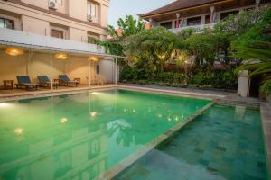 a swimming pool in front of a building at Palm Garden Kuta in Kuta