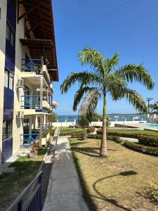 a palm tree next to a building next to the beach at Apto lindo em Alter do chão in Alter do Chao