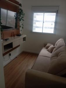 a living room with a couch and a television at Apartamento frente ao mar com piscina, a 5 minutos da Cachoeira 1 quarto in Mongaguá
