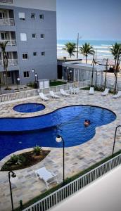 a person swimming in a swimming pool next to a building at Apartamento frente ao mar com piscina, a 5 minutos da Cachoeira 1 quarto in Mongaguá