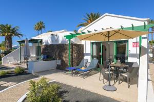Un patio con una mesa y sillas y una sombrilla. en Casa Victoria, en Playa Blanca