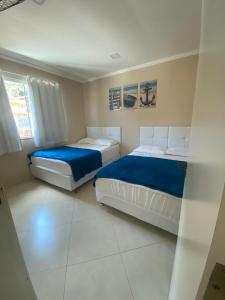 2 Betten in einem Zimmer mit weißen Fliesenböden in der Unterkunft Linda casa em Tarituba in Paraty